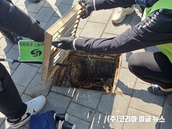 자원봉사자들이 맨홀 뚜껑을 열자 쓰레기와 담배꽁초가 쌓여 있었다. 