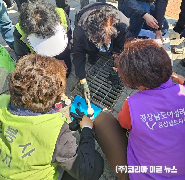 자원봉사자들이 우수관 안의 쓰레기를 다 치우고 우수관앞에 스티커를 붙이고 있다.